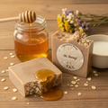 Oh Honey soap bars on a warm wooden surface with golden honey, rolled oats, milk, and dried wildflowers